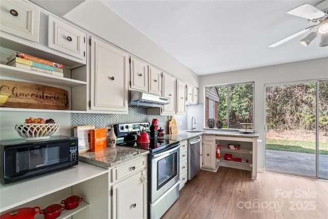 kitchen featuring under cabinet range hood, stainless steel appliances, a sink, a wealth of natural light, and open shelves