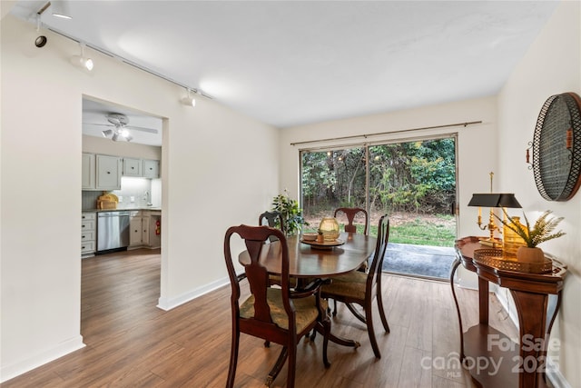 dining room with ceiling fan, wood finished floors, rail lighting, and baseboards