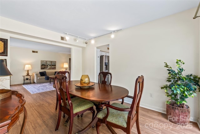 dining area featuring light wood-type flooring, baseboards, visible vents, and track lighting