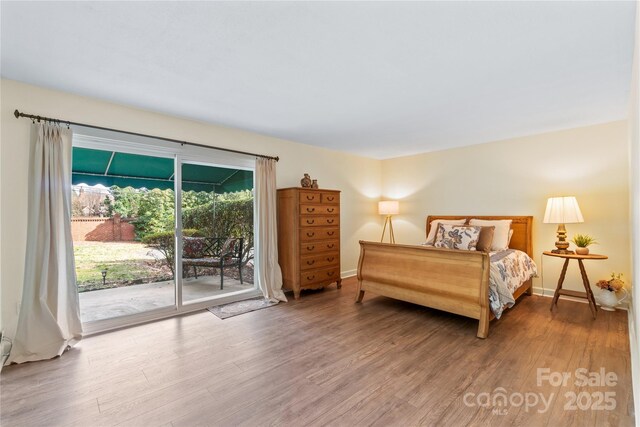 bedroom with access to outside, wood finished floors, and baseboards