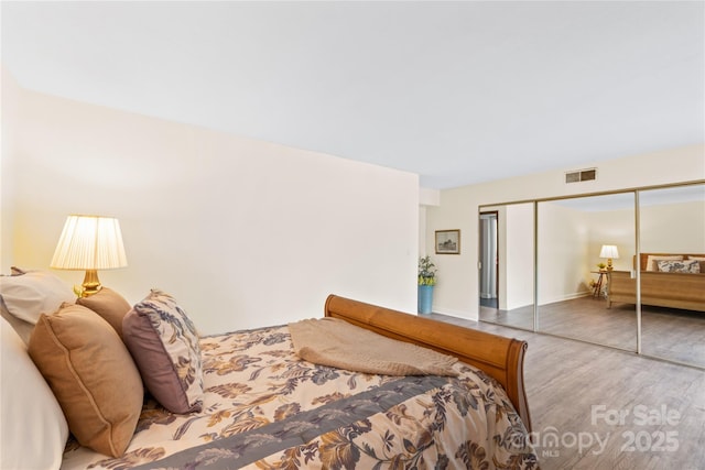 bedroom featuring a closet, visible vents, and wood finished floors