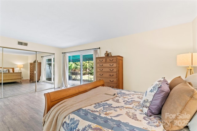 bedroom with access to outside, wood finished floors, and visible vents