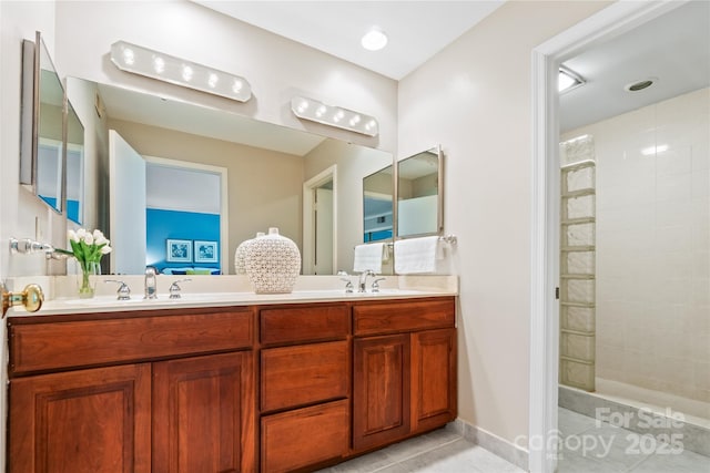 full bath featuring double vanity, a tile shower, and a sink