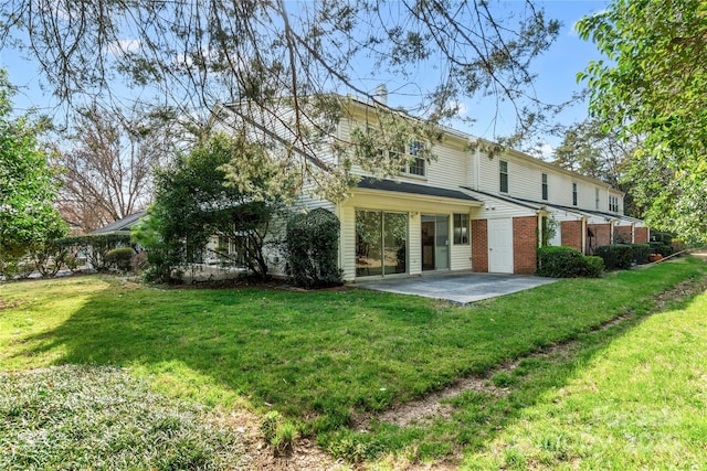 rear view of property with a patio area, a lawn, and brick siding