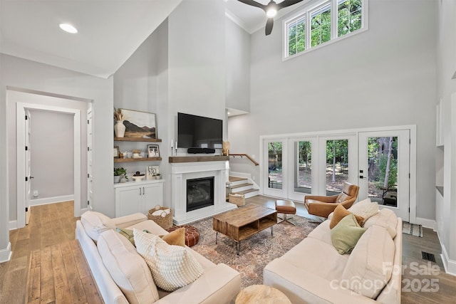 living room with a high ceiling, crown molding, and light wood-type flooring