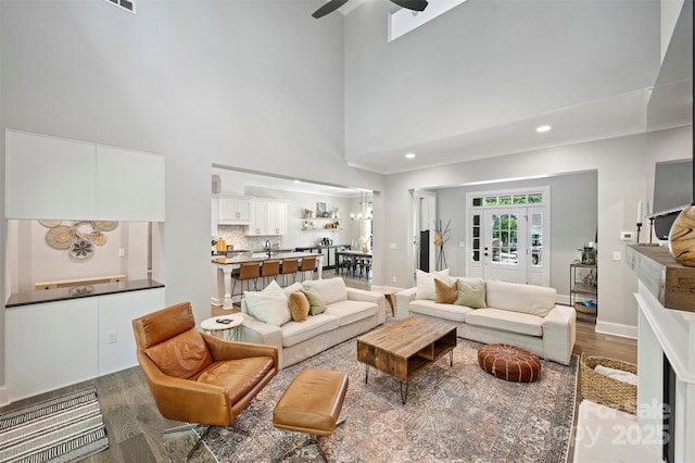 living room featuring sink, wood-type flooring, ceiling fan, and a high ceiling