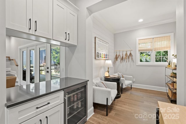 kitchen featuring white cabinetry, ornamental molding, light hardwood / wood-style floors, and beverage cooler