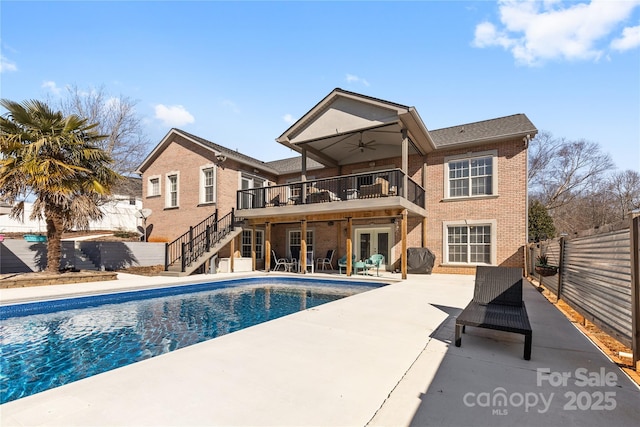 rear view of property with a fenced in pool, ceiling fan, a patio, french doors, and a balcony