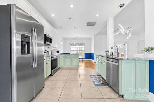 kitchen with appliances with stainless steel finishes, kitchen peninsula, green cabinets, and white cabinets