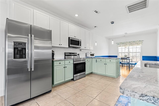 kitchen featuring tasteful backsplash, hanging light fixtures, green cabinets, stainless steel appliances, and white cabinets