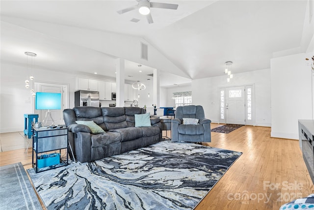 living room featuring ceiling fan, vaulted ceiling, and light wood-type flooring