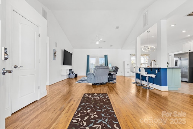 living room with ceiling fan, high vaulted ceiling, sink, and light hardwood / wood-style floors