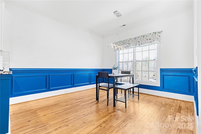 dining area featuring crown molding and light hardwood / wood-style floors