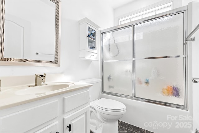 full bathroom featuring vanity, combined bath / shower with glass door, and toilet