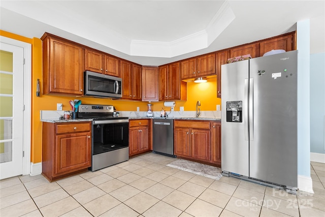 kitchen featuring light stone counters, stainless steel appliances, a tray ceiling, and sink