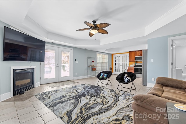 living room featuring french doors, ceiling fan, a raised ceiling, and light tile patterned floors