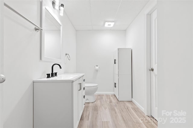 bathroom with vanity, wood-type flooring, toilet, and a paneled ceiling