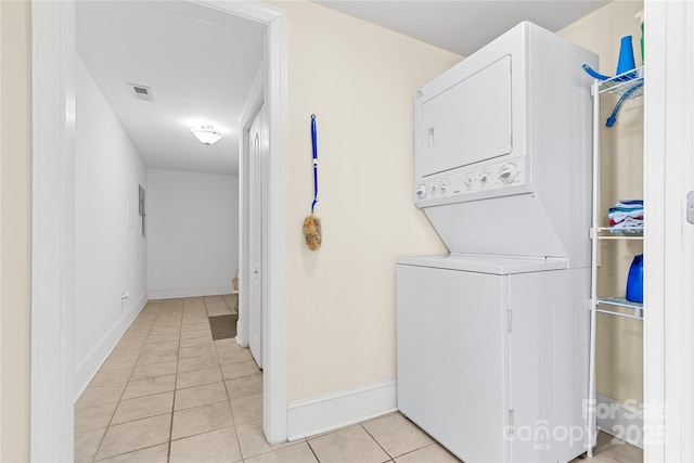 laundry area with stacked washer and dryer and light tile patterned floors