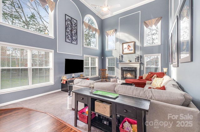 living room with crown molding, a towering ceiling, a high end fireplace, and wood-type flooring