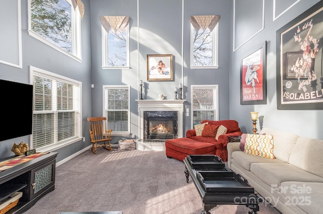 carpeted living room featuring a high end fireplace and a high ceiling