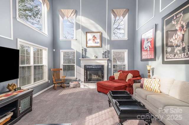 carpeted living room featuring a high end fireplace and a high ceiling