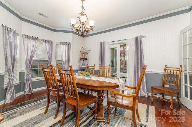 dining room featuring dark wood-type flooring, crown molding, and a notable chandelier