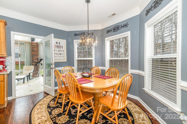 dining room with ornamental molding, dark hardwood / wood-style flooring, and a notable chandelier