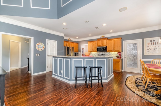 kitchen with a breakfast bar, stainless steel appliances, dark hardwood / wood-style floors, a center island with sink, and decorative backsplash