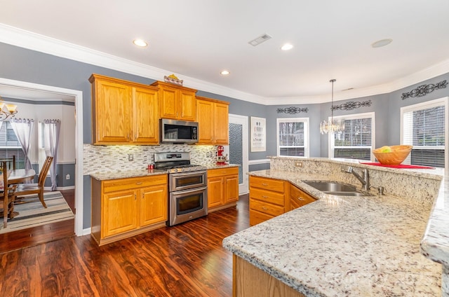 kitchen with sink, backsplash, light stone counters, stainless steel appliances, and an inviting chandelier