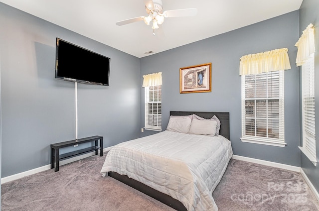 carpeted bedroom featuring multiple windows and ceiling fan