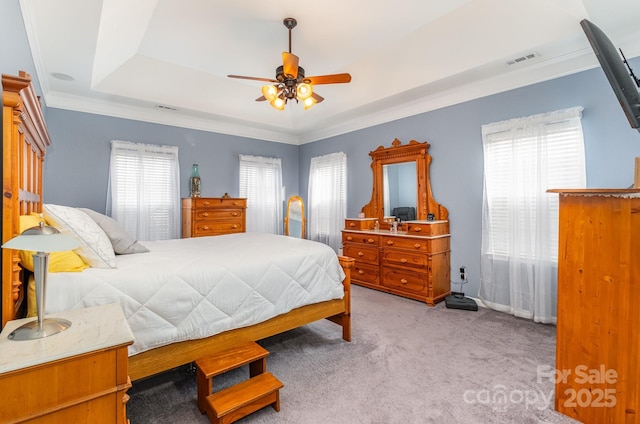 bedroom featuring crown molding, a tray ceiling, light colored carpet, and ceiling fan