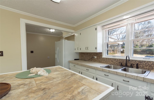 kitchen with tasteful backsplash, sink, white cabinets, white refrigerator with ice dispenser, and crown molding