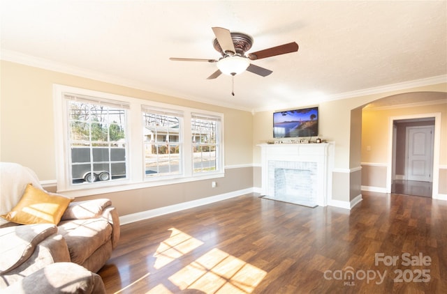 unfurnished living room featuring dark hardwood / wood-style flooring, a brick fireplace, ornamental molding, and ceiling fan