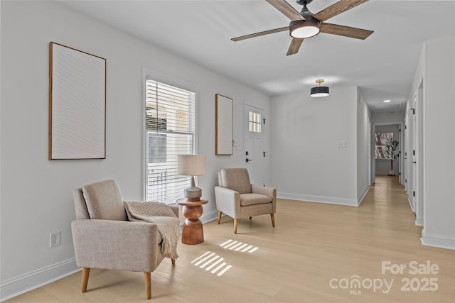 living area with light hardwood / wood-style floors and ceiling fan