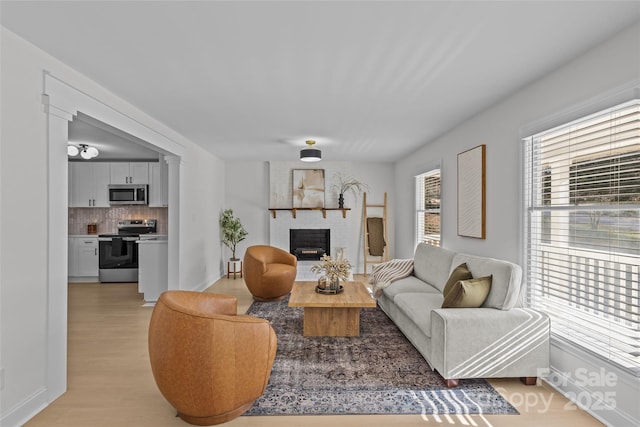 living room with a brick fireplace and light hardwood / wood-style flooring