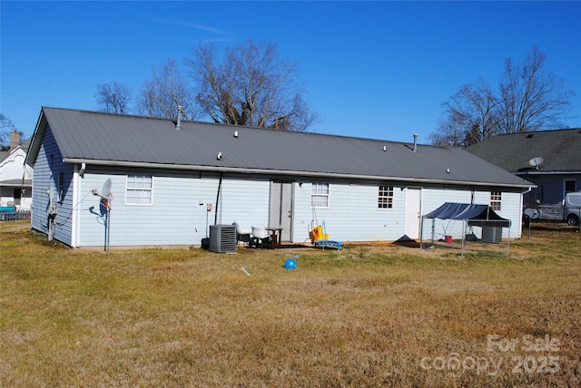 rear view of property with cooling unit and a yard