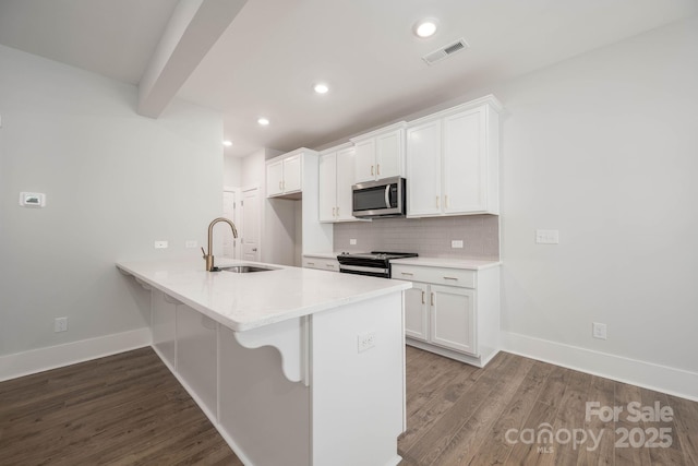 kitchen with dark wood-type flooring, sink, white cabinetry, stainless steel appliances, and decorative backsplash