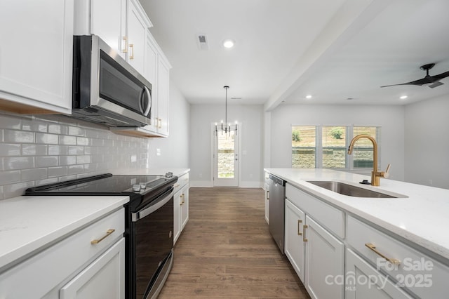 kitchen with pendant lighting, sink, white cabinets, decorative backsplash, and stainless steel appliances