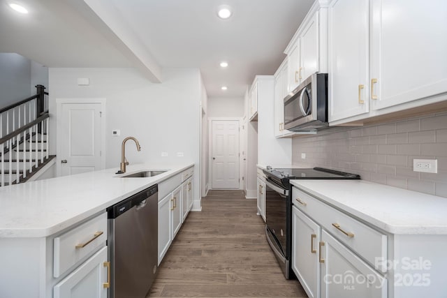 kitchen featuring appliances with stainless steel finishes, hardwood / wood-style floors, sink, white cabinets, and backsplash