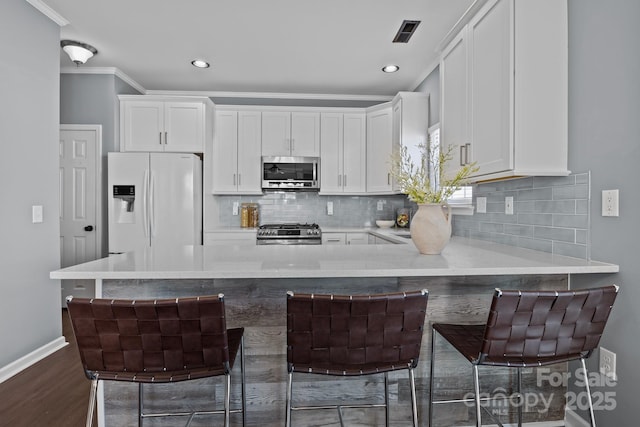 kitchen featuring stainless steel appliances, backsplash, and white cabinets