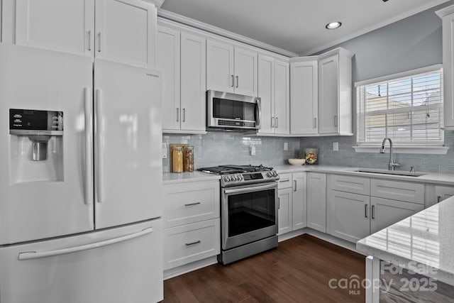 kitchen featuring backsplash, dark wood finished floors, appliances with stainless steel finishes, white cabinetry, and a sink