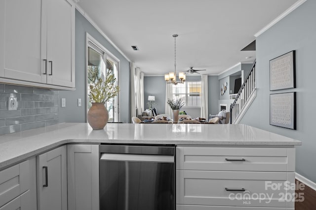 kitchen featuring light stone countertops, a peninsula, crown molding, a notable chandelier, and tasteful backsplash