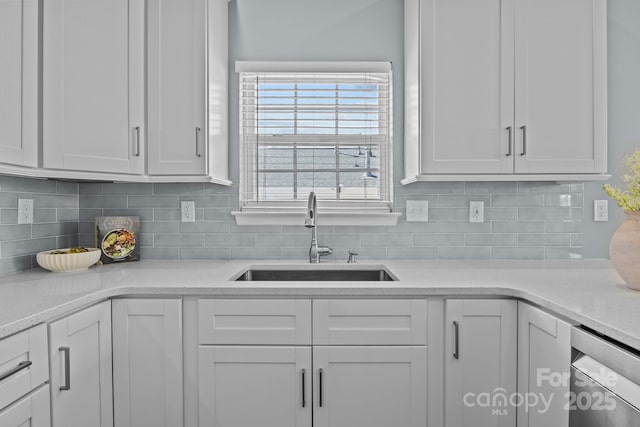 kitchen with white cabinetry, decorative backsplash, dishwasher, and a sink