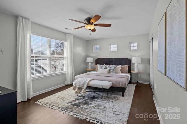 bedroom with ceiling fan, visible vents, baseboards, and dark wood finished floors