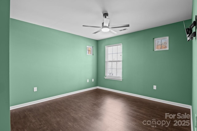 unfurnished room with dark wood finished floors, visible vents, baseboards, and ceiling fan