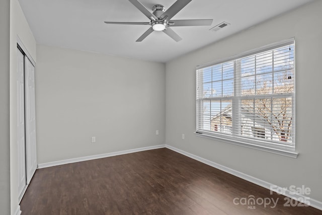 unfurnished bedroom featuring visible vents, a ceiling fan, dark wood-style floors, a closet, and baseboards