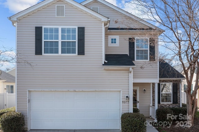 traditional home featuring an attached garage, concrete driveway, and fence