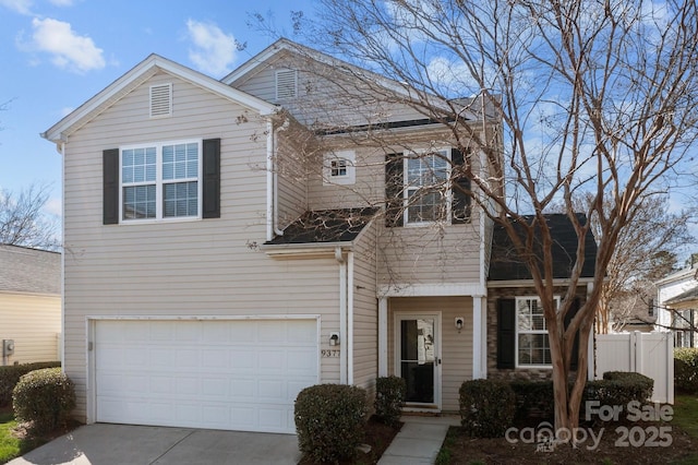 traditional-style house featuring concrete driveway, an attached garage, and fence