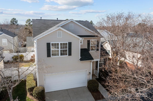 traditional-style home featuring a garage, driveway, and roof with shingles