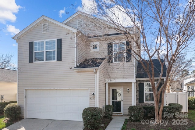 traditional home featuring a garage, driveway, and fence